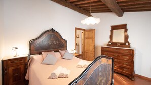 Ein Schlafzimmer mit einem hölzernen Bett, einem Nachttisch, einer Kommode und einem Spiegel.
