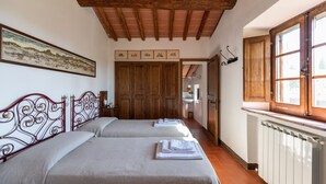 Una habitación con dos camas, vigas de madera en el techo, un ventanal grande y un cuadro en la pared.