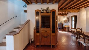 Un mueble de madera con puertas de cristal, una escalera y un comedor con sillas y una mesa de madera.