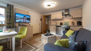 A modern living room with a sofa, a dining table, and a kitchen area. - Vacation apartment Grünstein, 1-2 persons, 30 sqm, upper floor (Schönau am Königssee)