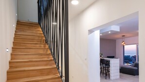Um interior moderno com escadaria de madeira, área de jantar com vista e um espaço de estar acolhedor.