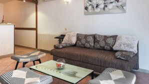 Een woonkamer met een bruine bank, decoratieve kussens, een glazen salontafel en stoelen met een hondentanden patroon.