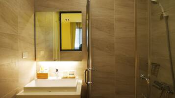 Un baño moderno con cabina de ducha de vidrio, un lavabo blanco y un espejo encima.