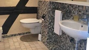 A bathroom with a toilet, sink, and tiled floor. - Single Room - Fachwerk-Hotel Eisenbart (Hann. Münden)