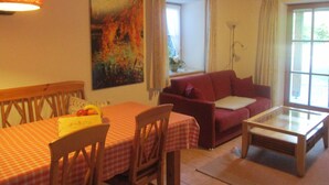 Une pièce comprenant une table à manger, des chaises, un canapé, une table basse en verre et un tableau accroché au mur.
