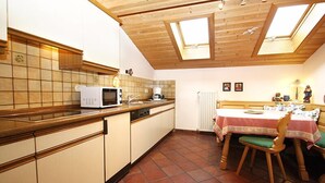 Eine Küche mit Holzausstattung, einer Mikrowelle und einem Esstisch mit Stühlen.