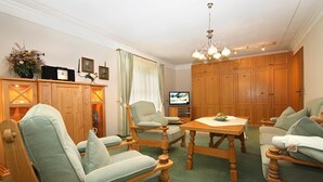 A living room with wooden furniture, a television, and a chandelier.