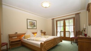 A traditional bedroom with a wooden bed, bedside tables, a chair, and a desk.