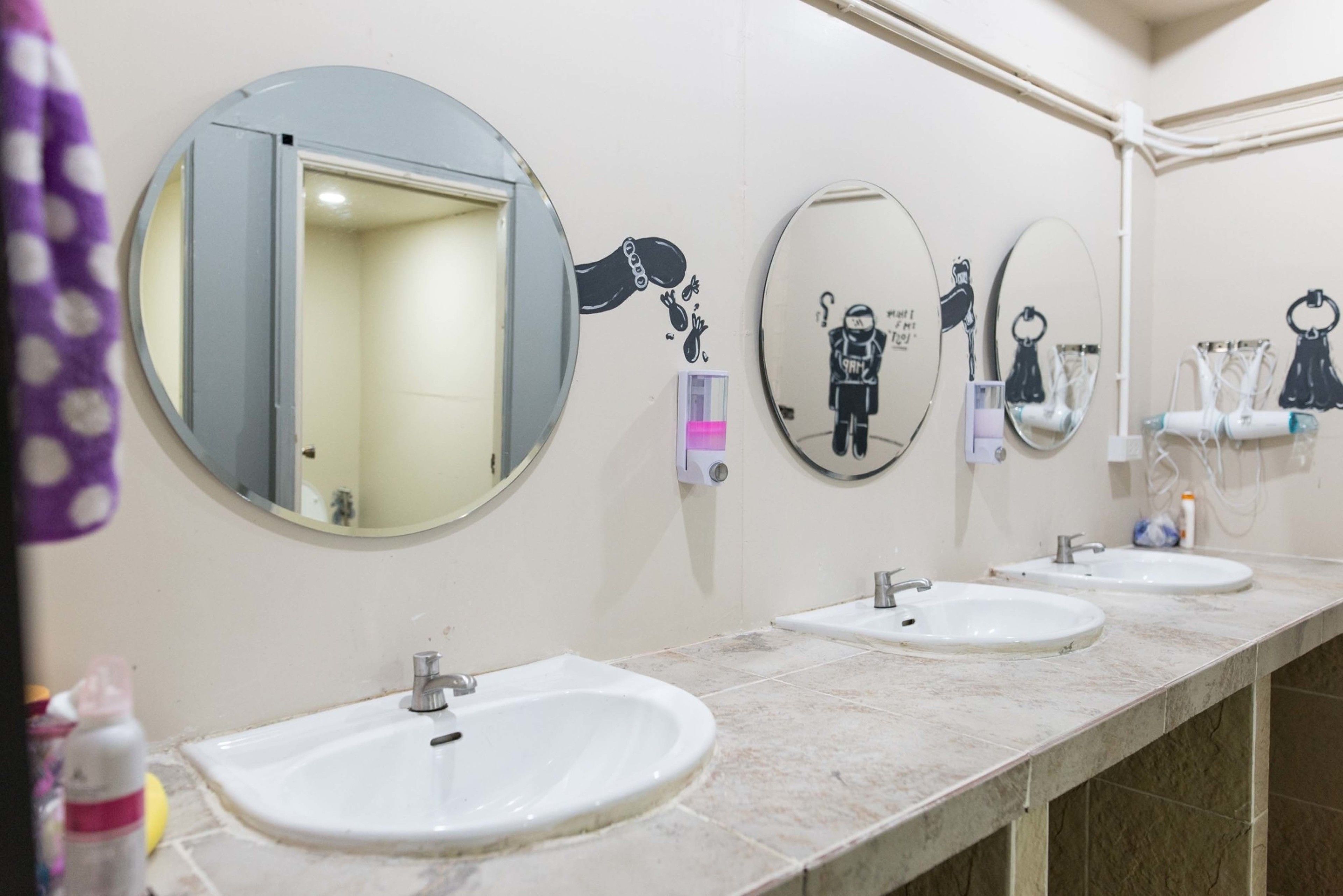 A bathroom with three sinks, a hairdryer, and mirrors.