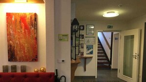 A hotel lobby with a red sofa, a painting, a staircase, and a door.