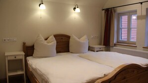 A bedroom with a wooden bed, two bedside tables, a nightstand, and a window with curtains.