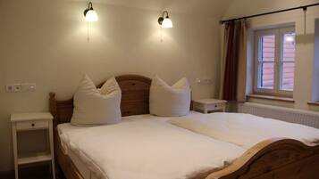Ein Schlafzimmer mit einem hölzernen Bett, zwei Nachttischen, einem Beistelltisch und einem Fenster mit Vorhängen.