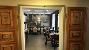 A restaurant with wooden doors, a tiled floor, and tables with chairs.