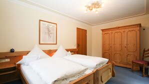 A bedroom with a wooden bed, a wooden wardrobe, a chair, and a framed picture on the wall. - Apartment 2, 98sqm, balcony, kitchen, 2 bedrooms, 1 living room, max. 2 pers. (Ruhpolding)