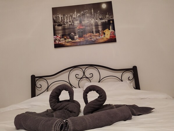 A bed with a cityscape view, a neatly folded towel, and a decorative item resembling a swan. - Rawabi Apartment (Rawabi)