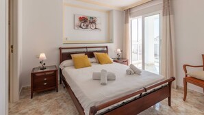 A neatly arranged bedroom with a bed, two bedside tables, a chair, and a window with curtains.