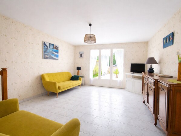 A living room with a yellow sofa, a TV, a lamp, and a cabinet.