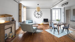 Un salon moderne comprenant un canapé, une table à manger et des chaises, une cheminée et une grande horloge murale.