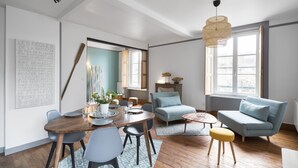 Un salon spacieux comprenant un coin repas, un canapé et une table basse. Une grande fenêtre offre une belle vue et permet à la lumière naturelle d’entrer.