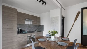 Une cuisine moderne avec des meubles de couleur bois foncé, un îlot central et un coin repas comprenant une table et des chaises en bois.