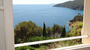 A coastal view from a balcony with a railing, overlooking a calm sea and a hilly landscape with trees. - 3-room apartment 75m², 2 terraces, direct access to calanques, WIFI, private parking (Cavalaire-sur-Mer)