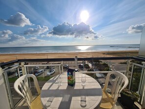 Un balcon avec une table et des chaises donnant sur une plage.