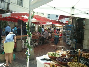 A bustling outdoor market with various stalls selling fruits, olives, and other goods. - 3000 sq f, in the old Saumur city , along the Loire river. Charm & great views (Saumur)