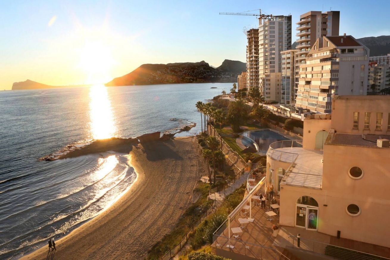 A coastal hotel with a beach view, multiple floors, and a construction crane in the background.