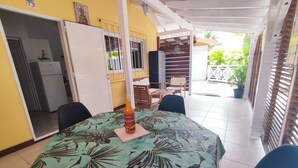 Een kamer met een tafel, stoelen, een fles en een deur naar een balkon.