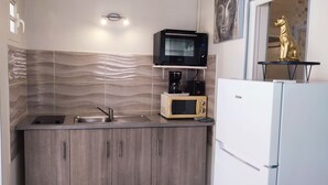 Een kleine keuken met een ingebouwde magnetron, koffiezetapparaat en een koelkast.