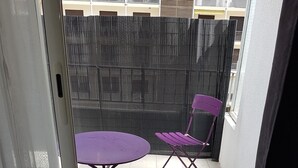A balcony with a table and two chairs, a black mesh fence, and a building in the background. - Elegant F1 all comfort, quiet city center terrace, parking 10 min center<br> (Ajaccio)