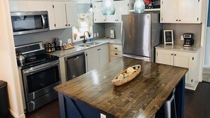 Una cocina moderna con electrodomésticos de acero inoxidable, una isla de madera e iluminación colgante.