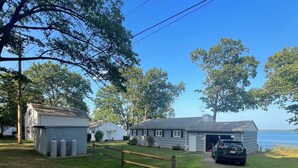 A house with a gravel driveway, a wooden fence, and a car parked in front.