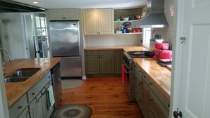 A kitchen with wooden countertops, a stainless steel refrigerator, and a stove.