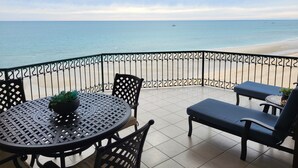 A balcony with a view of the beach, a round table with chairs, and a potted plant. - As seen on HGTV! Sonoran Sea, Beach Front, Stunning Ocean Views,2B/2B, 8th Floor (Puerto Peñasco)