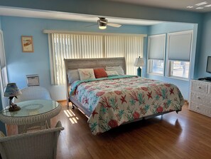 Een slaapkamer met een houten bed, een plafondventilator en een raam met jaloezieën.