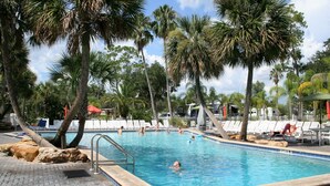 Ein Swimmingpool, umgeben von Palmen und Liegestühlen.
