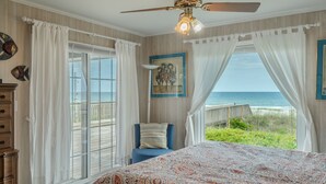 A bedroom with a large bed, a ceiling fan, and a view of the ocean. - Loony Dunes | Direct Beach Access + Sound Front Dock (Topsail Beach)