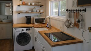 A compact kitchen with a washing machine, microwave, and wooden countertops.