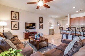 A living room with a ceiling fan, a TV, and a dining area with chairs and a table.
