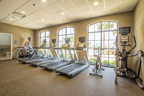 Et fitnesscenter med løbebånd, crosstrainere og en motionscykel.