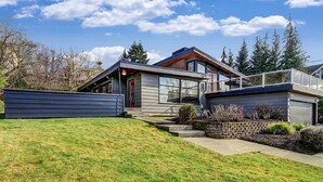 Een modern huis met twee verdiepingen, een garage, een overdekte veranda en een verzorgd gazon.