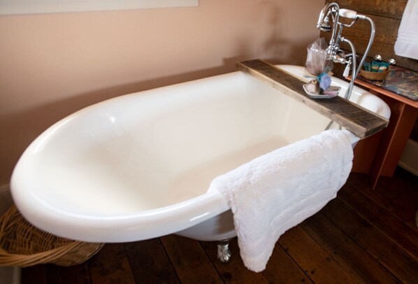 A white freestanding bathtub with a wooden tray and a towel. - Historic Pioneer Cabin in the Heart of Canyon Country (Escalante)