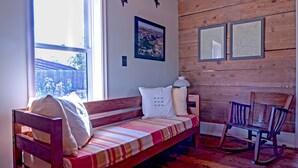 A wooden interior with a wooden bench, a rocking chair, and a window with a view. - Historic Pioneer Cabin in the Heart of Canyon Country (Escalante)