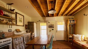 A rustic kitchen with wooden beams, a wooden dining table, and a bench. - Historic Pioneer Cabin in the Heart of Canyon Country (Escalante)