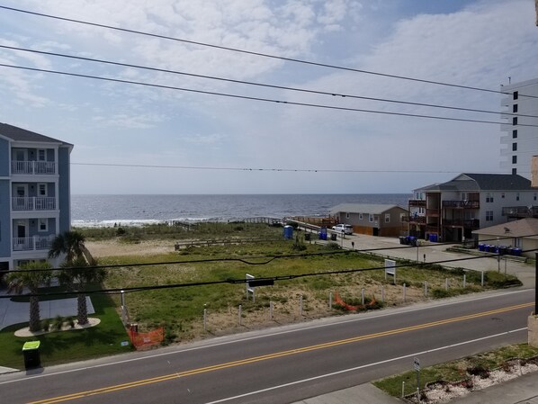 Vista costera con carretera, acceso a la playa y edificios.
