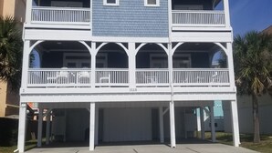 A multi-story building with a balcony on each floor, a garage entrance, and a clear sky.