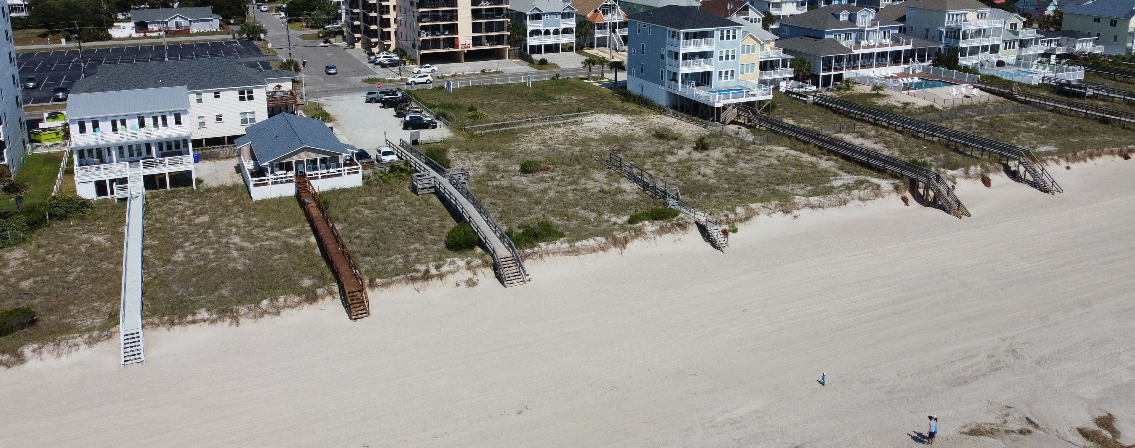 Vista aérea de una zona residencial costera con casas, una playa y un muelle.