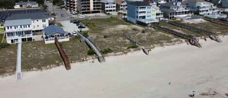 Vista aérea de una zona residencial costera con casas, una playa y un muelle.