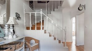 Una escalera con barandillas blancas y escalones de madera que sube a un segundo piso.
